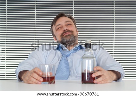 Sorrow business man sitting at a table with a bottle on a light background