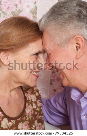 A beautiful pair of older people sitting together on a pink background