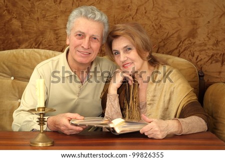 Beautiful Caucasian good couple of elderly people sitting on a brown background