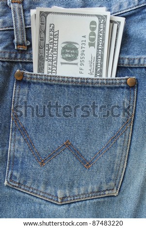 Pocket money. New dollar  in hip pocket of worn blue jeans close-up.