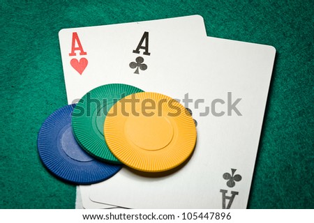 Pair of aces and poker chips on a green table in casino