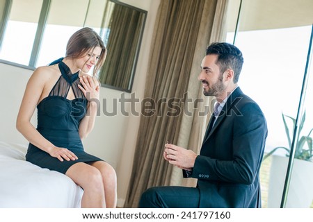Young man making a marriage proposal to his girlfriend in hotel.