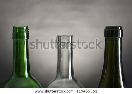 Picture of wine bottle necks on a row, on a grey and black background