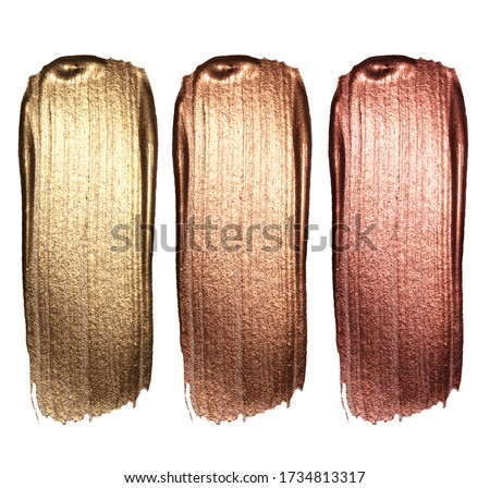 Creative brushstrokes of gold paint isolated on a white background. Gold paint texture.Acrylic gold paint. Smears of cosmetics, blush, highlighter, eye shadow, lipstick.