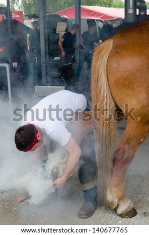 IPSWICH, UK - MAY 30: A blacksmith shoeing a horse on the Suffolk show held on May 30, 2013 in Ipswich, UK. It is an annual farming and agricultural show with daily revenue over Â£500000 in 2012.