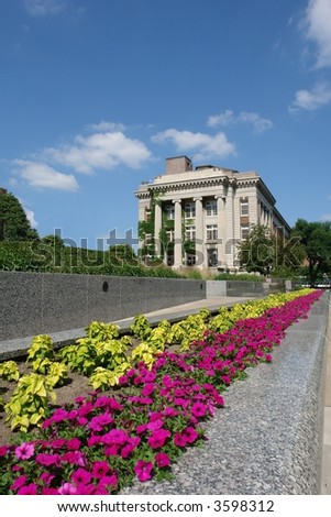 A picture pink violets and green plants converging toward a majestic building