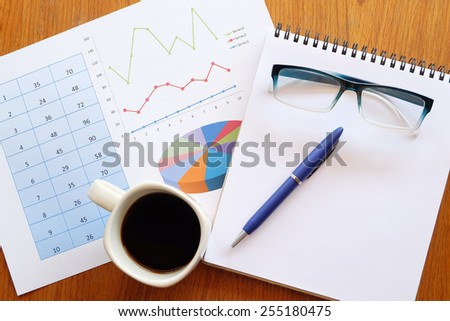note book and chart on the wooden table with back coffee
