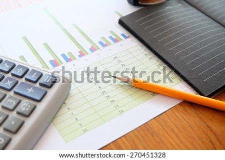 note book and chart on wooden background with business concept