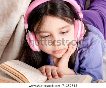 Little girl read a book and listen music