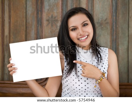 Asian Indonesian female pointing at blank sign board with a big smile on her face.