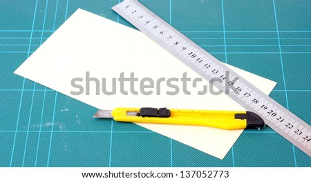 knife, paper, and ruler on the cutting board