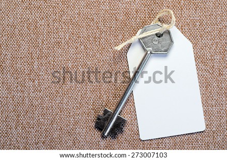 white paper tag attached to the metal silver key on the brown background