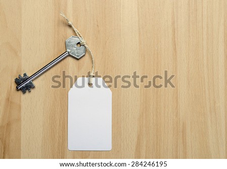 white paper tag attached to the metal silver key on the wooden background