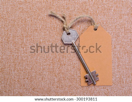 brown paper tag attached to the metal silver key on the brown background