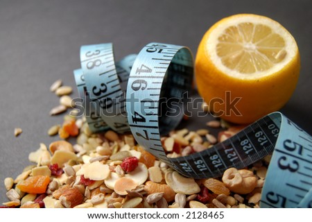 This is an image of a lemon, measuring tape and some country mix fruit/cereal.