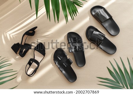 Summer women's shoes. Black heeled sandals, flat sandals, rubber slippers and tropical palm leaves on beige background. Trendy female footwear. Flat lay, top view. Foto d'archivio © 