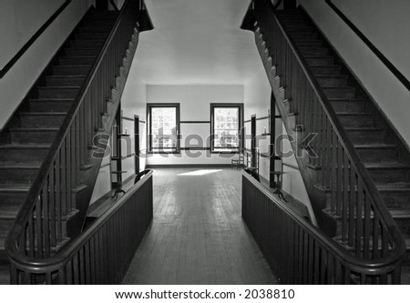 Center hallway of a 19th century boarding house with two symmetric staircases.  Black and white.