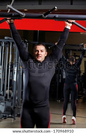 Young man training in the gym with heavy balls.Low light.