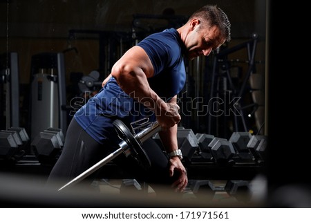 very power athletic guy , execute traction with dumbbells, exercise on broadest muscle of back, in sport hall