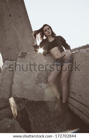 Beautiful young woman posing outdoor in a wall background at sunset.Fashion colors.Wide angle.