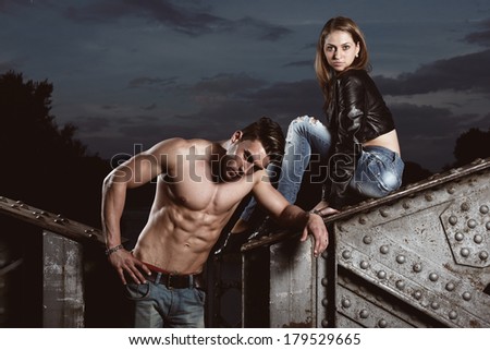 Sexy and fashionable couple wearing jeans, shoot in a grungy location - landscape orientation with copy-space .Fashion colors