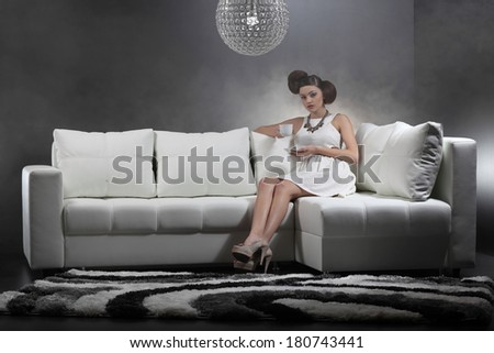 Beautiful elegant woman sitting on sofa and drinking coffee .Fashion colors .Fine art.