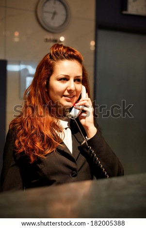 Hotel Concierge .Reception of hotel, desk clerk, woman taking a call and smiling.