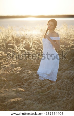 Beauty Romantic Girl Outdoors. Beautiful Teenage Model girl Dressed in Casual Short Dress on the Field in Sun Light. Blowing Long Hair. Autumn. Glow Sun, Sunshine. Backlit. Toned in warm colors