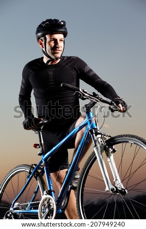 A young male riding a mountain bike outdoor at sunset.Fashion colors.
