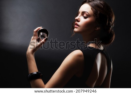 Elegant sensual young woman holding perfume, Beautiful woman face. Perfect makeup. Beauty fashion. Fashion photo