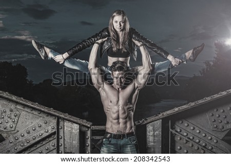 Outdoor natural portrait of a gorgeous couple fitness models.Gymnastics girl.Fashion colors. Photo has an intentional film grain) .Fine art.