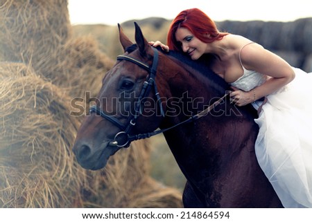 Fashionable  woman riding a horse in sunny day. Long curly hair. Fashion colors.