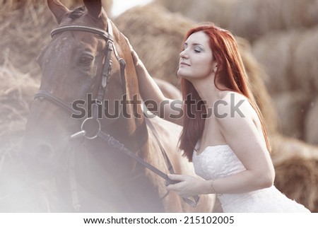 Fashionable woman riding a horse in sunny day. Long curly hair. Fashion colors.