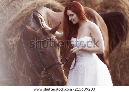 Fashionable woman riding a horse in sunny day. Long curly hair. Fashion colors.