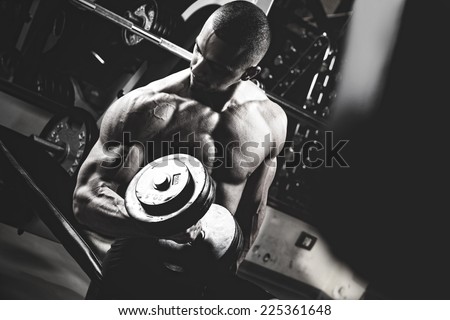 Closeup of a muscular young man lifting weights. Fine art. B&W