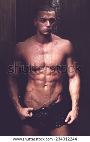 Sexy young muscle man in a shower wearing dark underwear