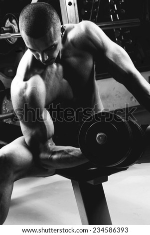 Closeup of a muscular young man lifting weights. Very power athletic guy, in sport-hall.