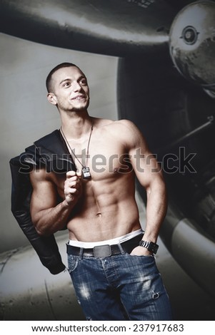 Attractive young muscle male model posing outdoors in leather jacket.Fashion colors