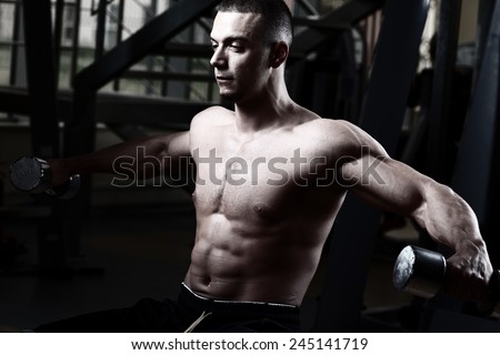 Very power athletic guy, execute exercise in sport hall. Closeup of a muscular young man lifting weights.