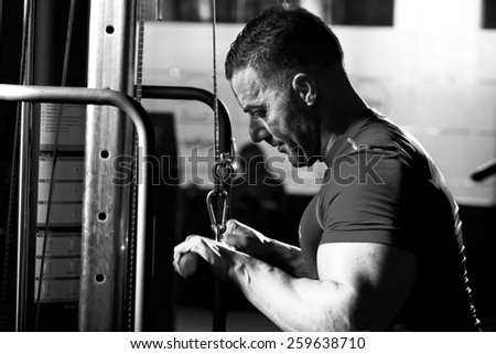 Handsome muscular bodybuilder.Muscular young man lifting weights on dark background