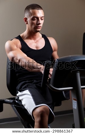 Stationary bicycles fitness man in a gym sport club. Close up.