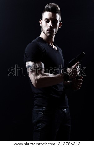 Portrait Of Young Man With Gun On Black Background