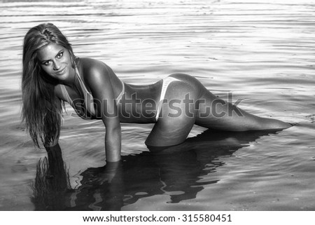 The beautiful bikini model posing against a setting sun on a body of water
