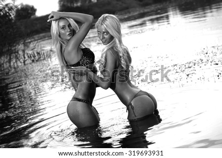 Two beautiful sexy girls posing in the warm water at sunset. B&W.