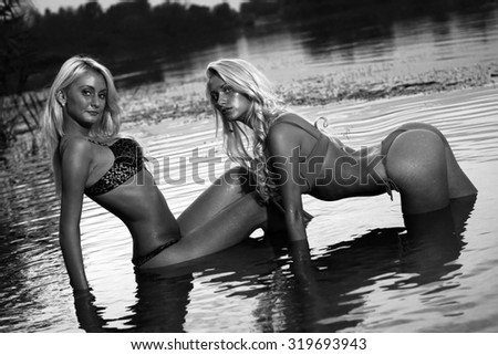 Two beautiful sexy girls posing in the warm water at sunset. B&W.