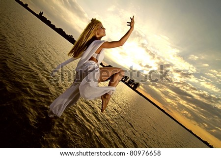 Blonde woman dressed in arab costume dancing in the warm  water on a beautiful sunset