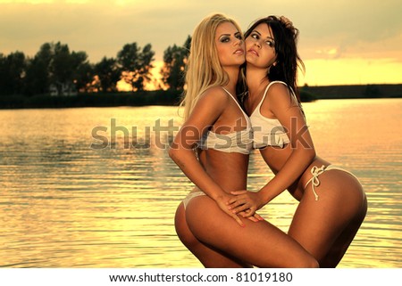 Beautiful girls posing in a warm water of a lake at sunset