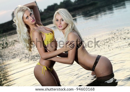 Two beautiful blonde girls in the warm water at sunset