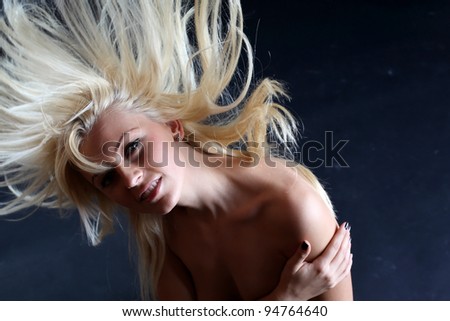 A beautiful blonde girl posing in a studio while playing with her crazy hair.