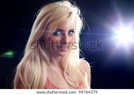A beautiful blonde girl posing in a studio.A flashing light in the background.